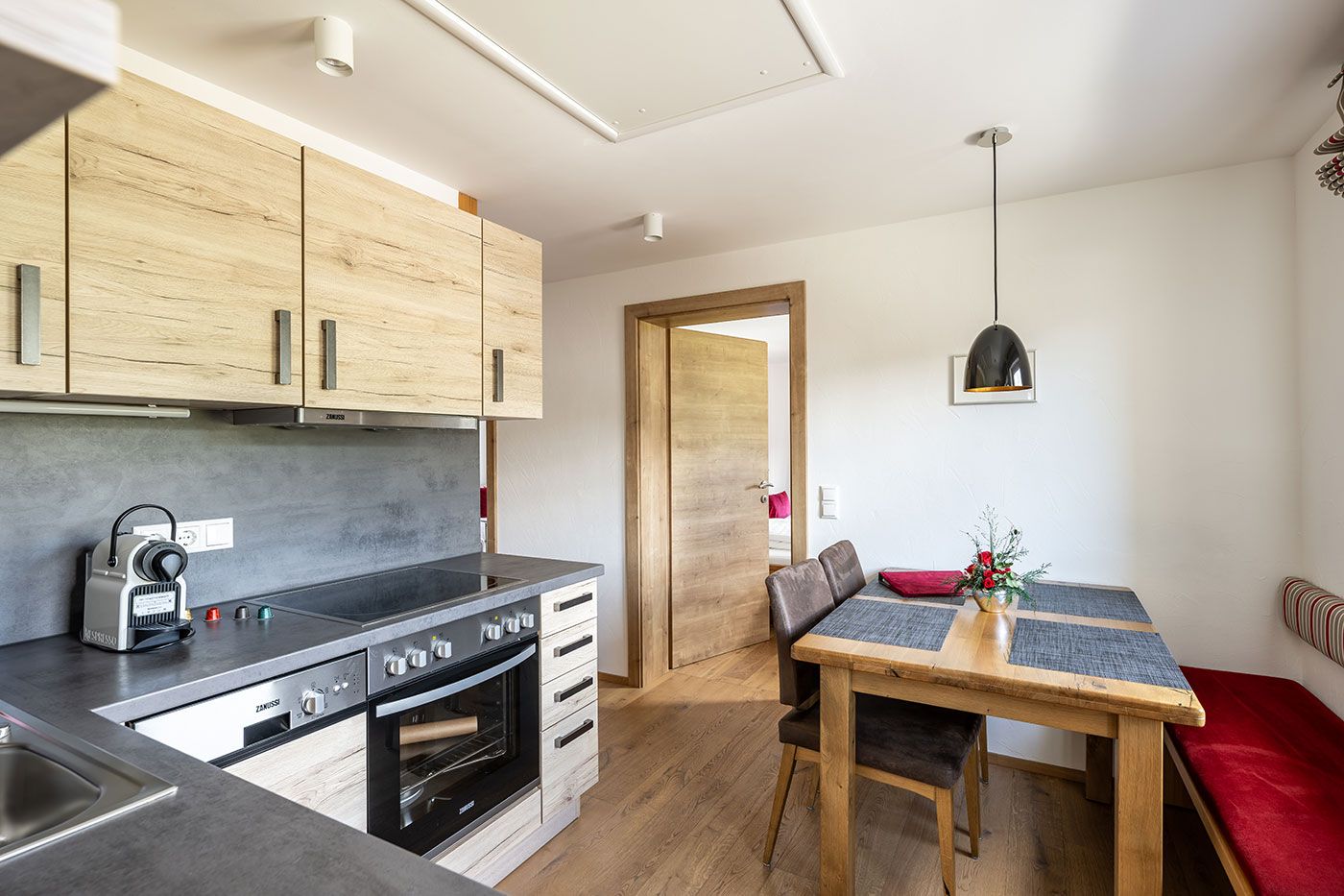 Küchenzeile und Esstisch des Apartments 4 mit Bank und 2 Stühlen sowie Fenster