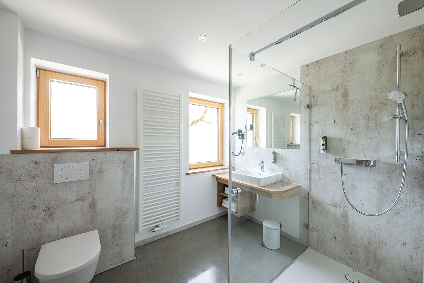 Geräumiges Badezimmer mit Fenstern, WC, Waschbecken und begehbarer Dusche