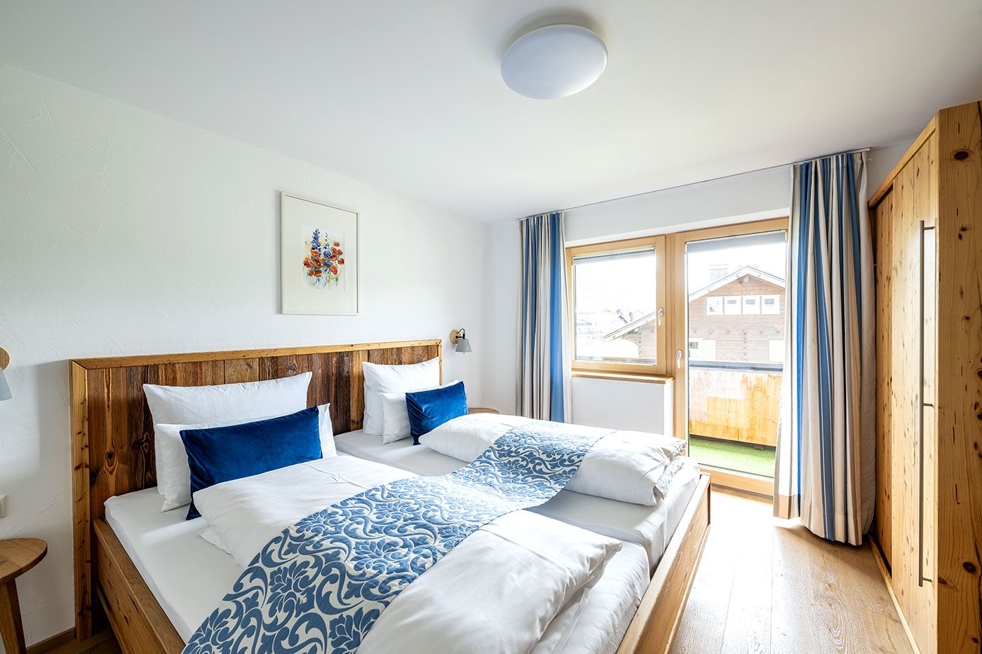 Helles Schlafzimmer mit Doppelbett, Schrank und Balkonzugang